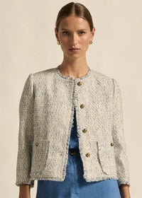 Woman wearing a textured beige jacket with gold buttons on a beige background