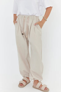 Person wearing beige pants and sandals on a white background