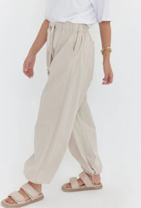 Person wearing beige wide-leg pants and sandals on a white background