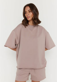 Woman wearing a beige oversized sweatshirt and shorts set on a white background
