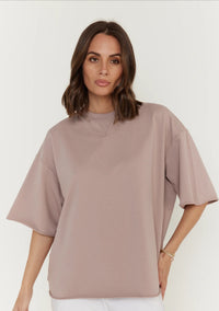 Woman wearing a beige oversized shirt against a white background