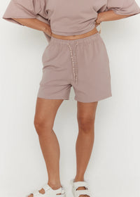 Person wearing a matching mauve top and shorts set on a white background