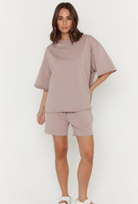Woman wearing a matching beige top and shorts set on a white background