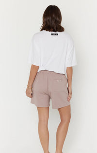 Person wearing a white t-shirt and beige shorts on a plain background