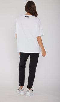 Person wearing a white oversized shirt and black pants on a plain background