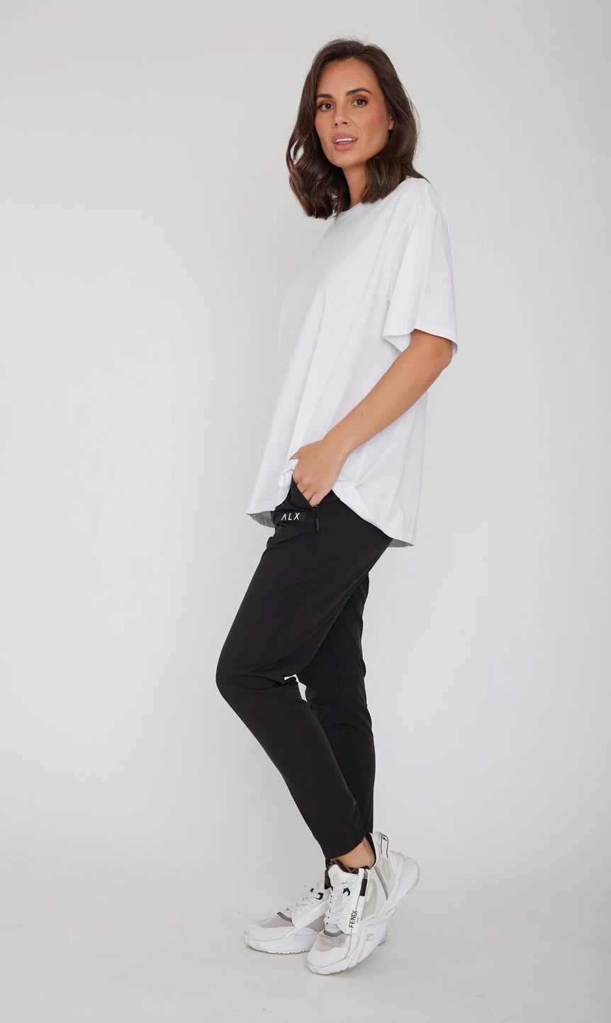 Woman wearing a white t-shirt and black pants on a plain background