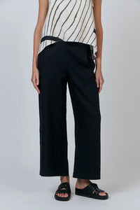 Person wearing black wide-leg pants and a striped top on a white background