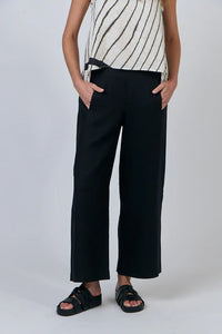 Person wearing black wide-leg pants and a striped top on a white background