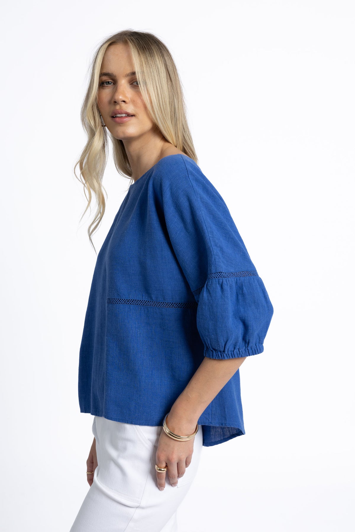 Woman wearing a blue blouse with white pants on a white background