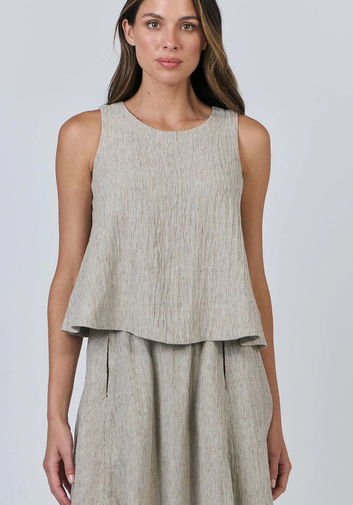 Woman wearing a sleeveless beige top and matching skirt on a plain background
