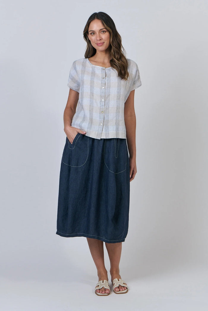 Woman wearing a white checkered shirt and blue skirt on a plain background