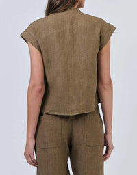 Person wearing a brown sleeveless top and pants on a light gray background