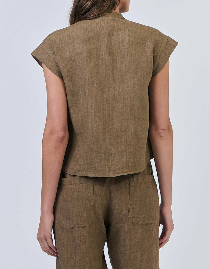 Person wearing a brown sleeveless top and pants on a light gray background