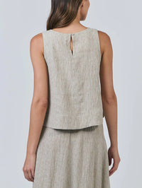 Woman wearing a beige sleeveless top and skirt set against a plain background