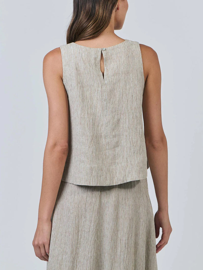 Woman wearing a beige sleeveless top and skirt set against a plain background