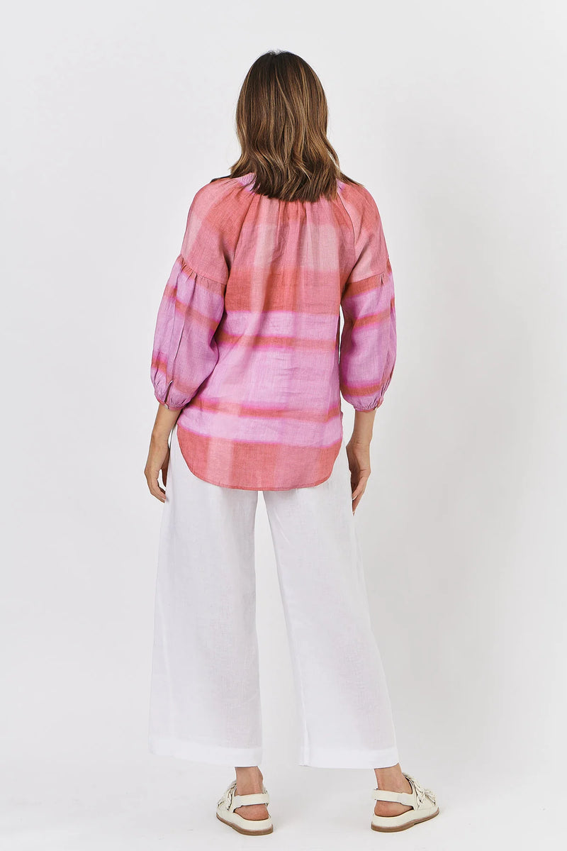 Person wearing a pink and purple striped shirt with white pants on a white background