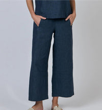 Person wearing dark blue wide-leg pants on a plain background