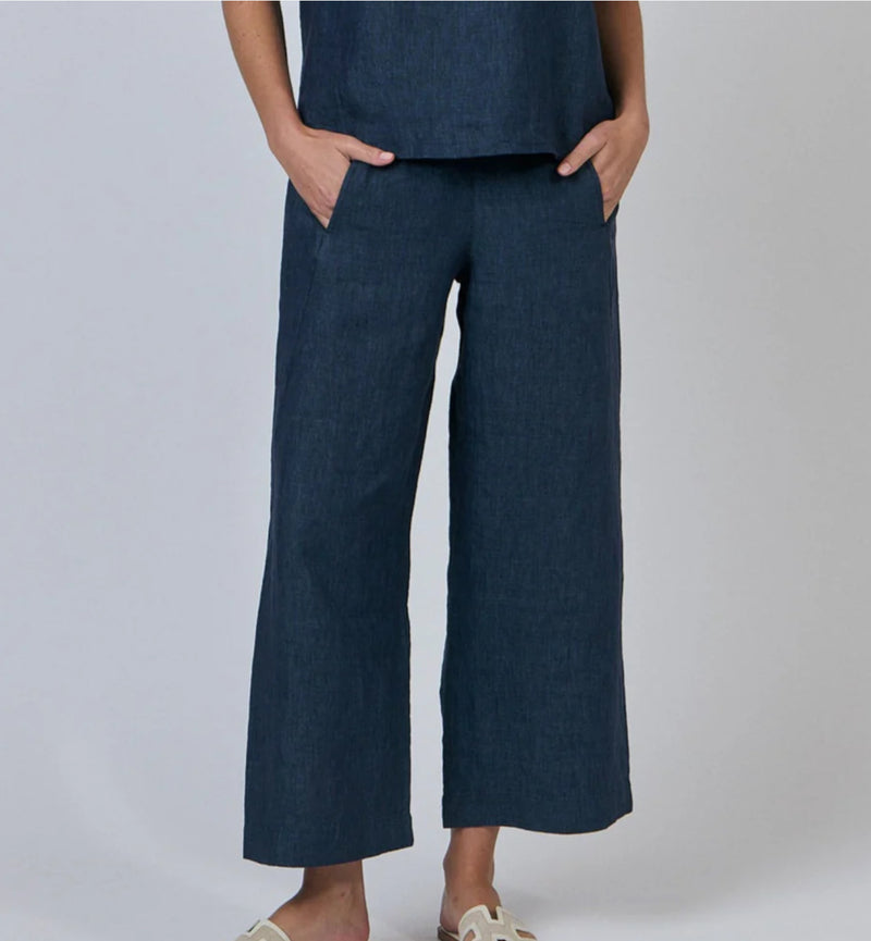 Person wearing dark blue wide-leg pants on a plain background