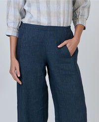 Person wearing navy wide-leg pants with a plain background
