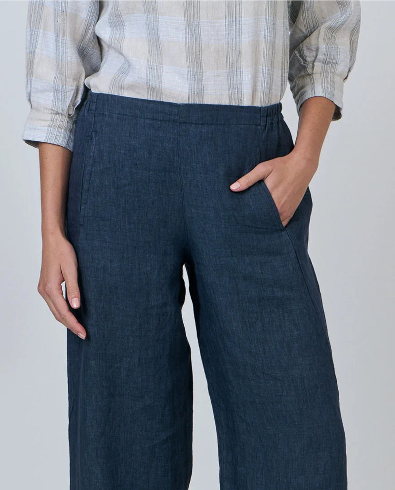 Person wearing navy wide-leg pants with a plain background