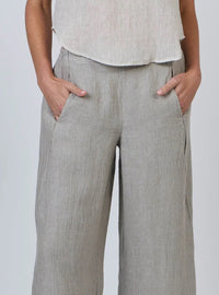 Person wearing light gray linen pants and a white top on a plain background