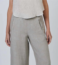 Person wearing light gray pants and a white top on a plain background