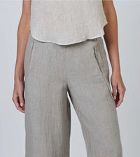 Person wearing light gray pants and a white top on a plain background
