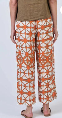 Orange and white patterned pants worn by a person on a white background