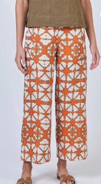 Person wearing orange and white patterned pants on a white background