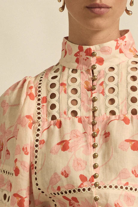 Close-up of a floral blouse with intricate detailing on a neutral background