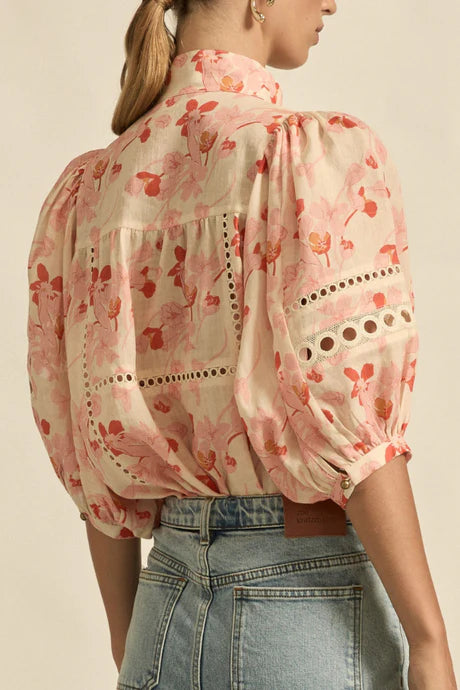 Floral blouse with balloon sleeves worn by a person on a beige background