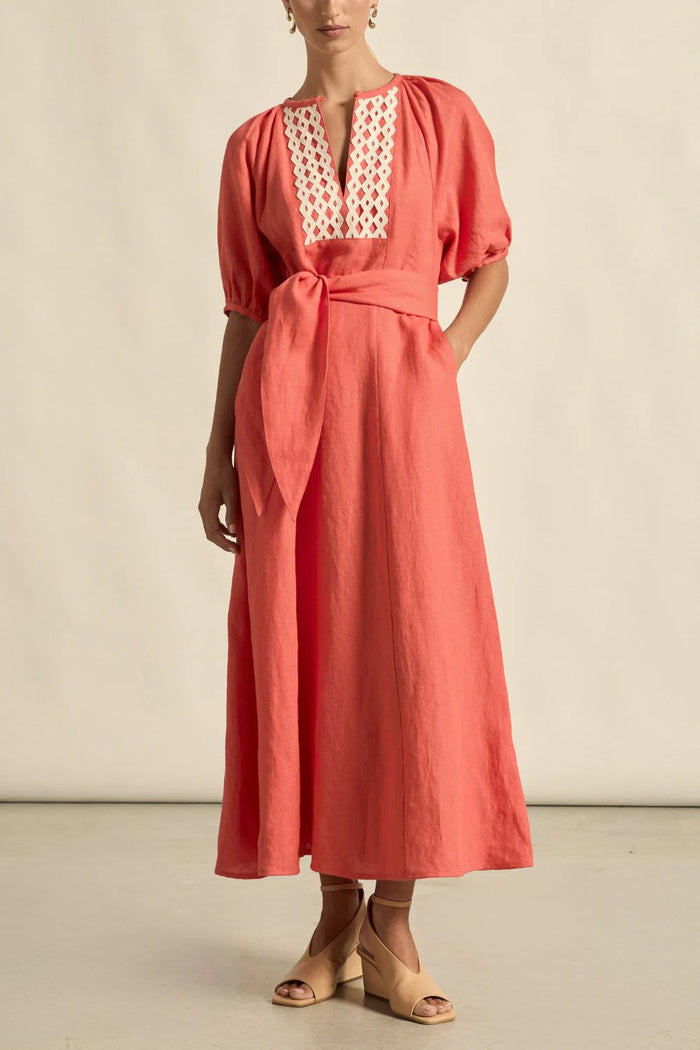 Coral dress with white lace detailing on a neutral background