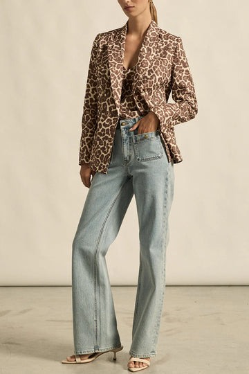 Person wearing a leopard print blazer and light blue jeans against a neutral background