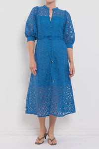 Woman wearing a blue lace dress against a white background
