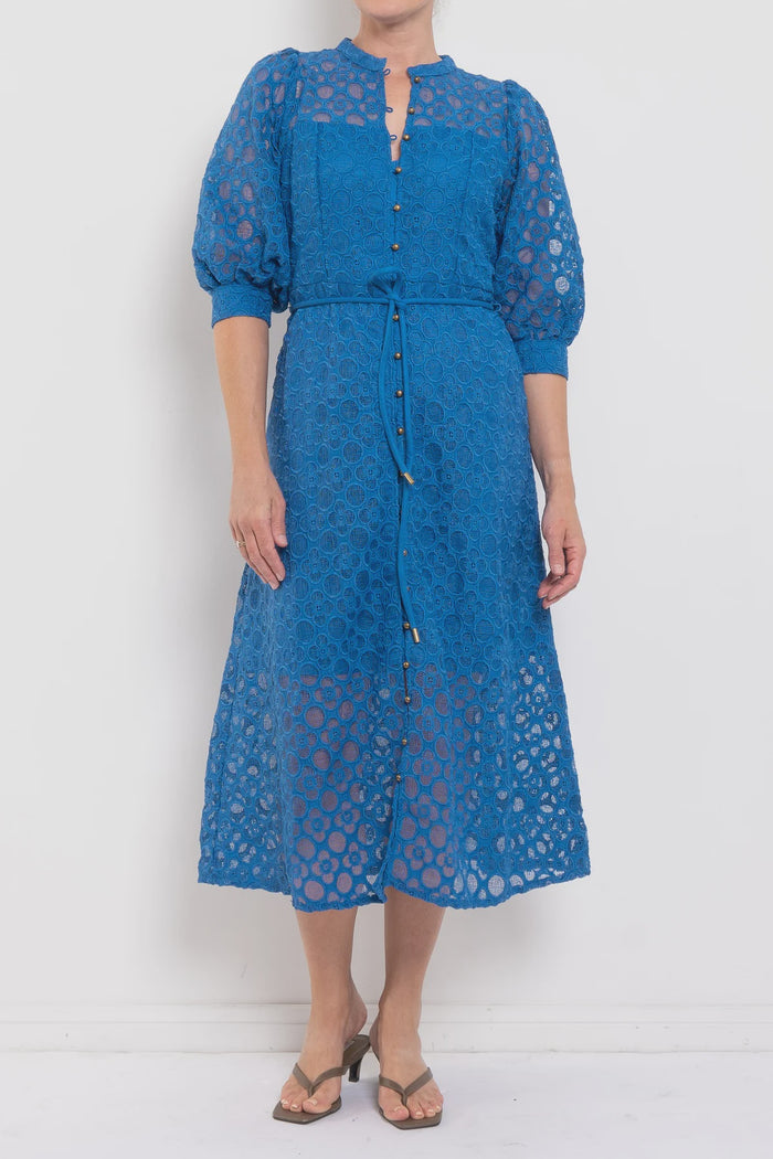 Woman wearing a blue lace dress against a white background