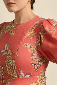Close-up of a coral-colored garment with intricate floral patterns on a neutral background