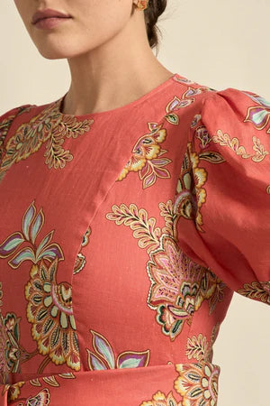 Close-up of a coral-colored garment with intricate floral patterns on a neutral background