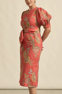 Woman wearing a red floral dress against a neutral background