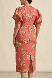 Woman wearing a red floral dress against a beige background