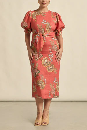 Woman wearing a red floral dress with puff sleeves against a beige background