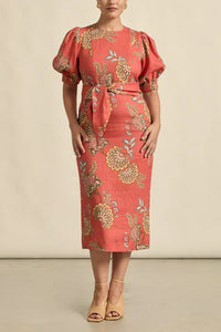Woman wearing a red floral dress with puff sleeves against a beige background