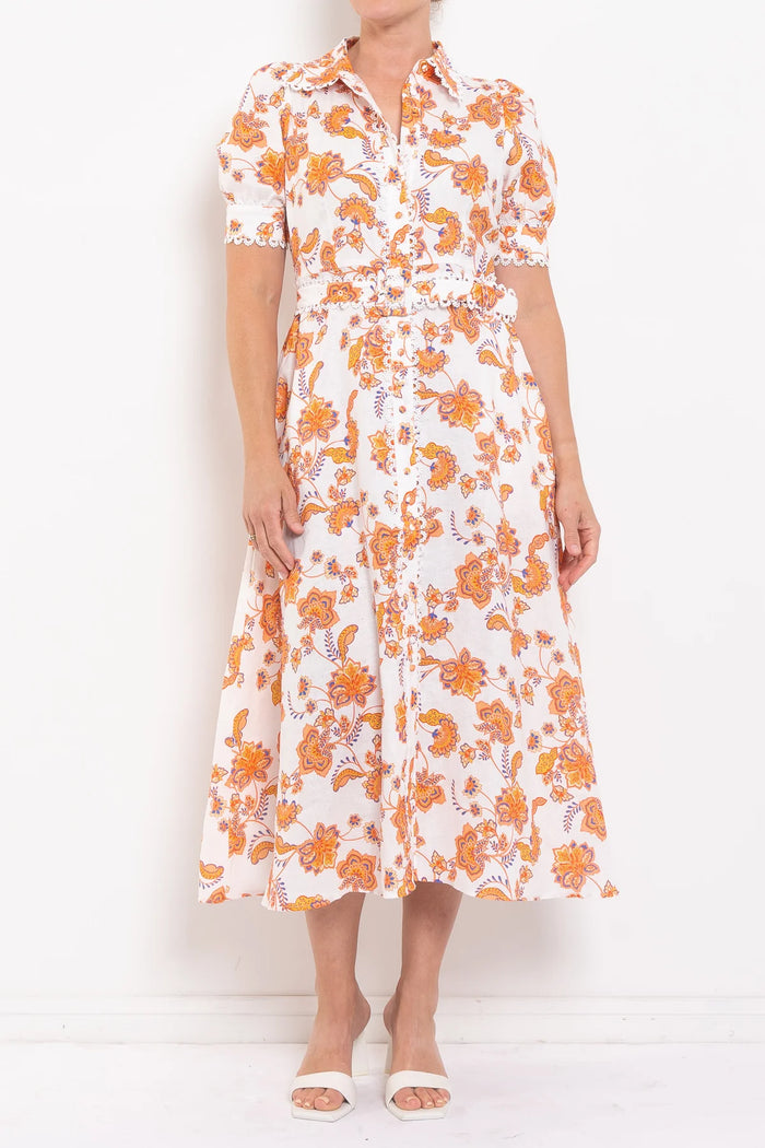 Woman wearing a white dress with orange floral pattern against a white background
