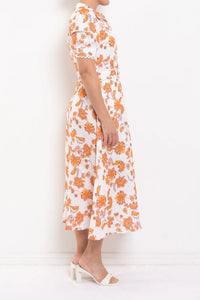 Woman wearing a white dress with orange floral pattern against a white background