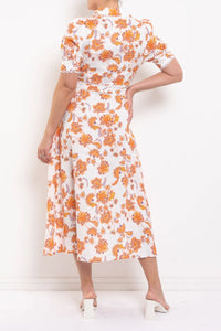 Woman wearing a white dress with orange floral pattern against a white background