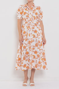 Person wearing a white dress with orange floral pattern against a white background