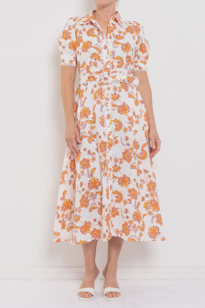 Person wearing a white dress with orange floral pattern against a white background