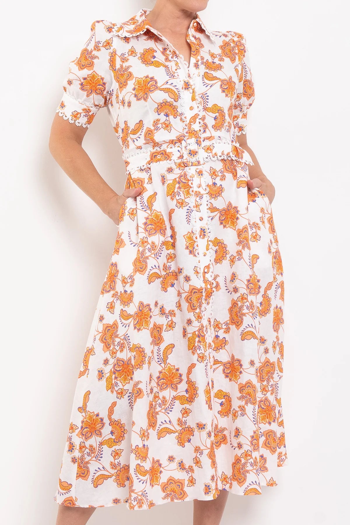 White dress with orange floral pattern worn by a person on a white background