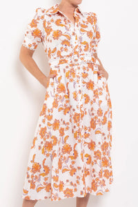 White dress with orange floral pattern worn by a person on a white background